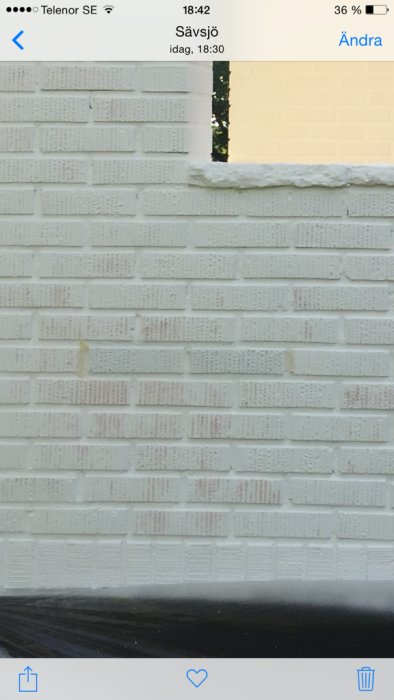 Vit silikatfärg på tegelhus som inte täcker helt, med röd tegelfärg som lyser igenom.