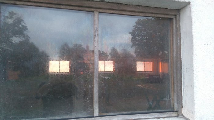 Fönsterruta som behöver tätas där den möter träramen, med synligt slitage och behov av underhåll.