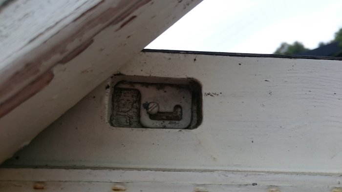 Närbild på urfräst spår i en fönsterkarm med ett till synes gammalt skruvlåst bleck.