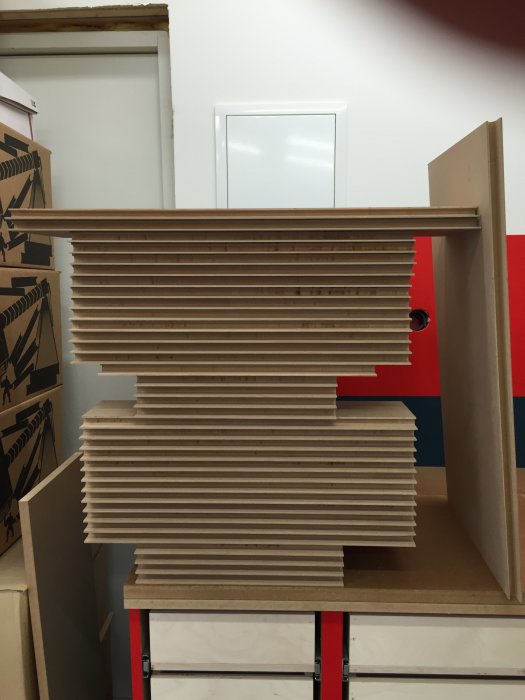 Stapel med 36 nyfrästa MDF-fonter på ett arbetsbänk i ett verkstadsutrymme.