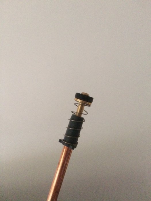 VVS-komponent med kägla och fjäder på ett kopparrör mot en suddig bakgrund.