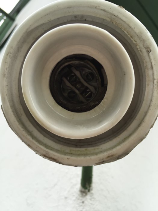 Utsikt över en öppen utebelysningsarmatur från ett 20-talshus, visar en lampsockel utan sin metallinsats.