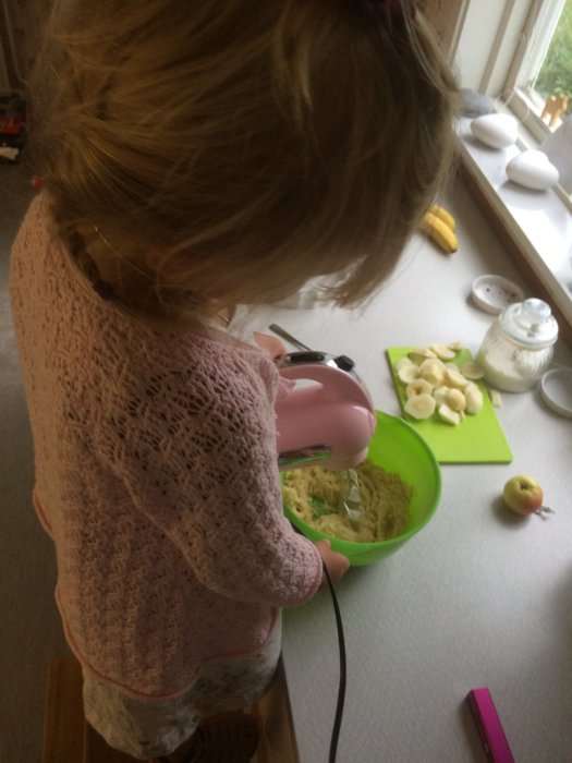 Barn som använder en elektrisk visp för att baka äppelpaj i ett kök.