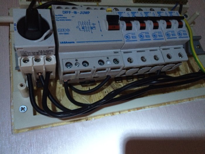 Elcentral med jordfelsbrytare och automatsäkringar monterade på träplatta. Kablar anslutna. Elektrisk installation.
