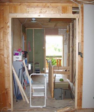 Renovering af væg mellem hall og stue, viser byggeåbning med træramme, værktøj og materialer synlige, trapperum bagved, del af gør-det-selv-projekt.