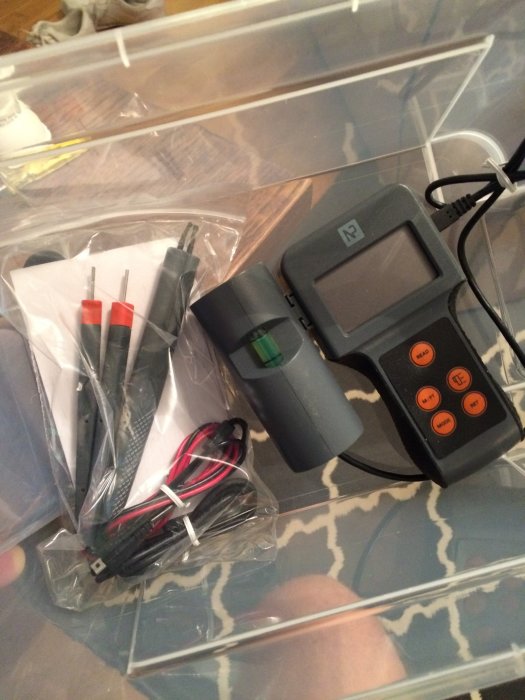 Multimeter med skärmar och kablar för att mäta spänning på ett kaklat golv.