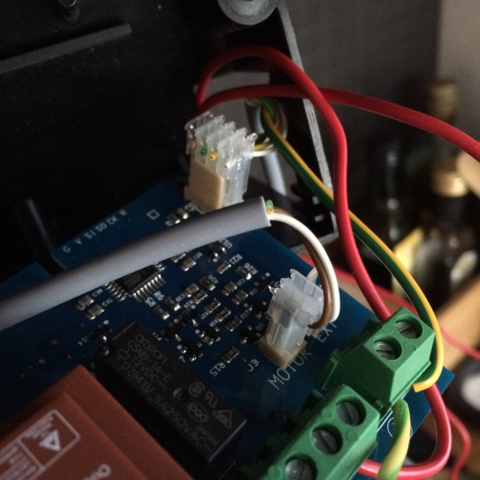 Elektronisk kretskort inkopplad med flertal kablar och terminalanslutningar i väntan på testning.