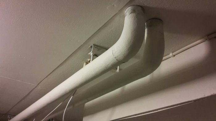 Isolerade vattenrör längs taket i ett förråd, möjligt område för installation av ballofix.