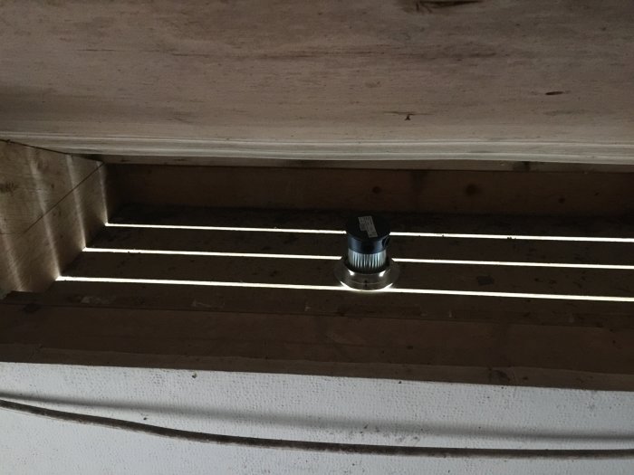 Takutsnitt med synliga takbjälkar och en installerad spot, utan isolering, med öppet ventilationsspace.
