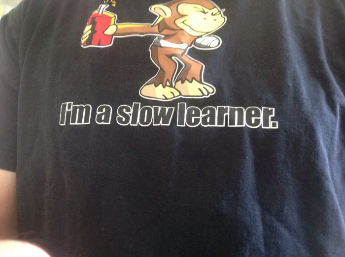 Illustration av en apa med en skollärarhatt och en text "I'm a slow learner" på en svart T-shirt.