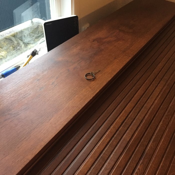 Renoverat möbellock med teakolja och vaxstänger med synlig förbättring av skador, bredvid verktyg.