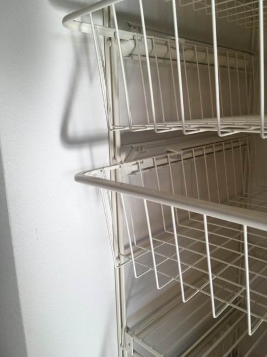 Vit trådhylla i en garderob, eventuellt från ett äldre garderobssystem.