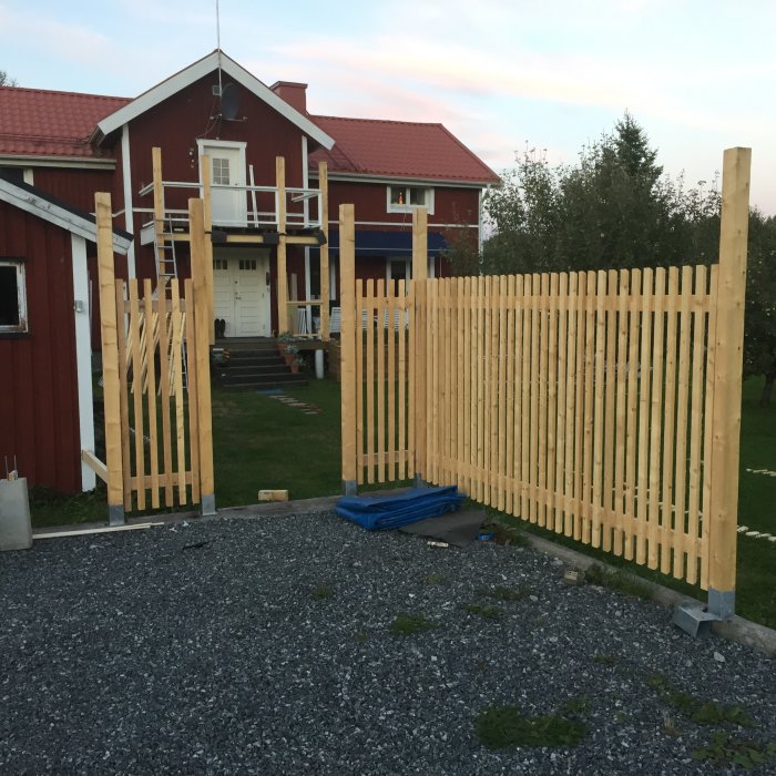 Delvis monterat träplank framför hus, med klippta balkskor och spjälor i varierande höjder.