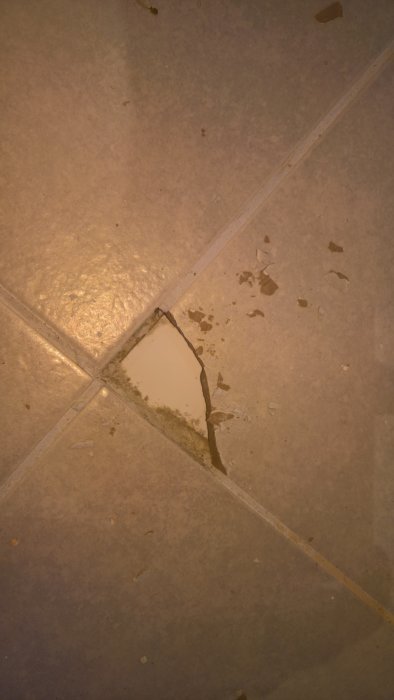 Illalagd klinkerplatta med sprickor och skador på ett badrumsgolv.