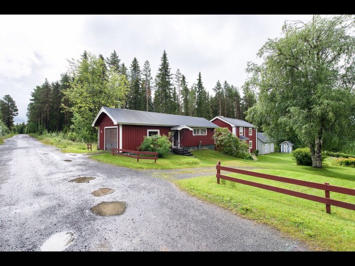 Rött trähus från 1912 med tillhörande grönskande tomt och sidobyggnad, beläget på landsbygden.