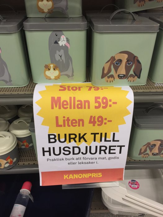 Reklamskylt för burk till husdjur med bilder av en hund och gnagare, och olika storlekar och priser.