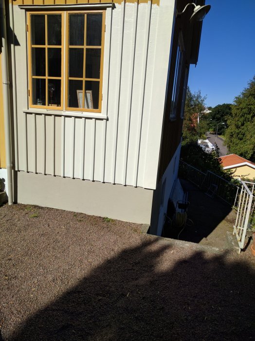 Husfasad i sol och skugga som visar olika nyanser på vägg och fönsterkarmar.