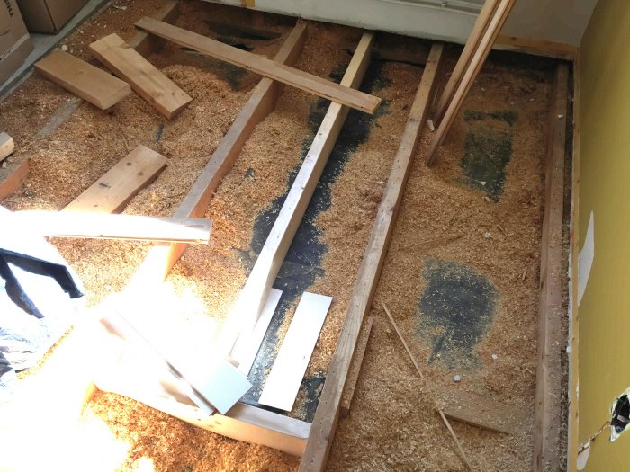 Golv under renovering med exponerat bjälklag och nya träreglar, spånskivor saknas.