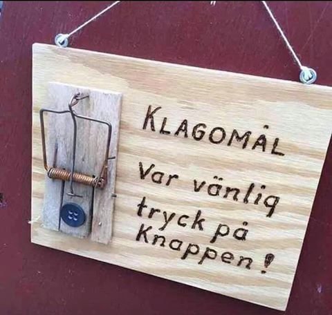 Skylt med texten "KLAGOMÅL Var vänlig tryck på knappen!" och en musfälla som 'knapp'.