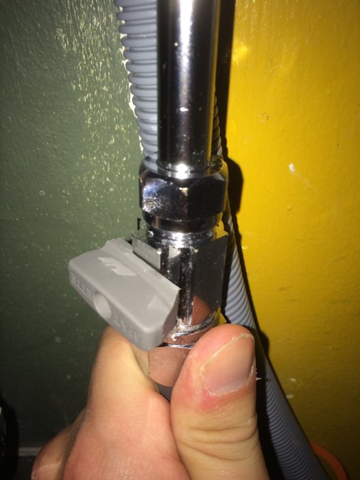 Närbild på en hand som håller en nyinstallerad rörkoppling med en läckande ballofixventil.