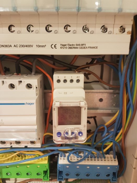 Elcentral med säkringar och en timer, omgiven av kablar och anslutningar.