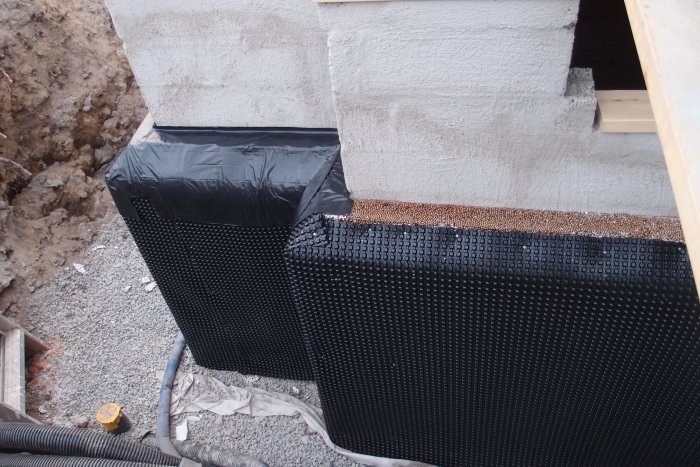 Grund av hus med dubbla isodränskivor och platonmatta, dräneringsgrus och fiberduk i grävd schakt.