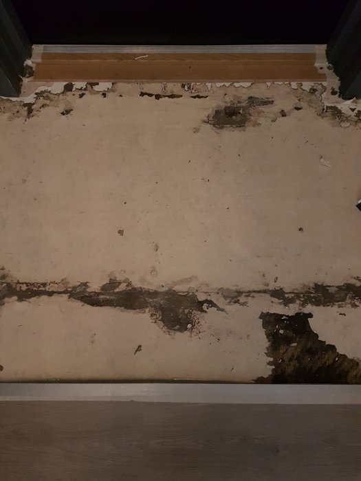 Golvyta med rester av lim och pappersskikt efter borttagen matta, behov av ytbehandling.