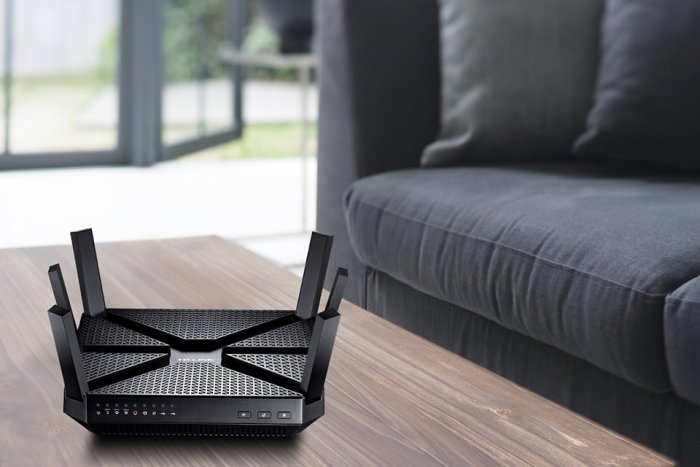 TP-Link Archer C3200 Wireless Tri-Band Gigabit Router på ett bord bredvid en mörk soffa.