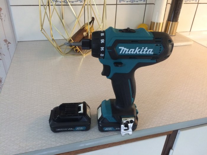 Makita skruvdragare med två olika storlekar av batterier och USB-dosa på ett köksbord.