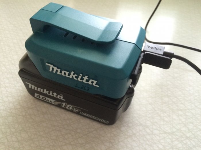 Makita verktygsbatteri med USB-adapter från Belkin ansluten, placerad på ett bord.