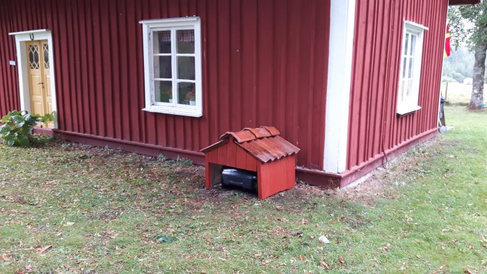 LPP-lösning med en luftvärmepump skyddad av ett rött minihus vid en faluröd stuga.