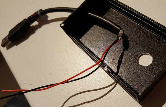 Öppen aluminiumlåda med elektronisk komponent och kablage för en repeater, inkluderar USB-kabel och lödda röda och svarta trådar.