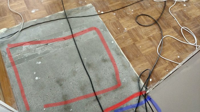 Golv med saknad mattsektion markerad i rött, omgivande trägolv och övergång till betong med list.