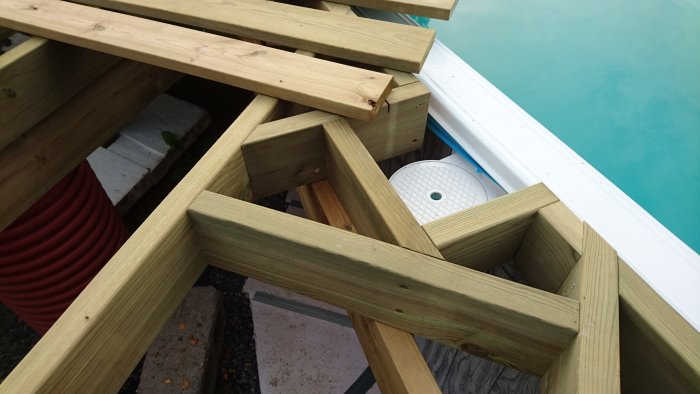 Nyinköpta 45x145 träreglar i pågående byggprojekt vid poolkant.