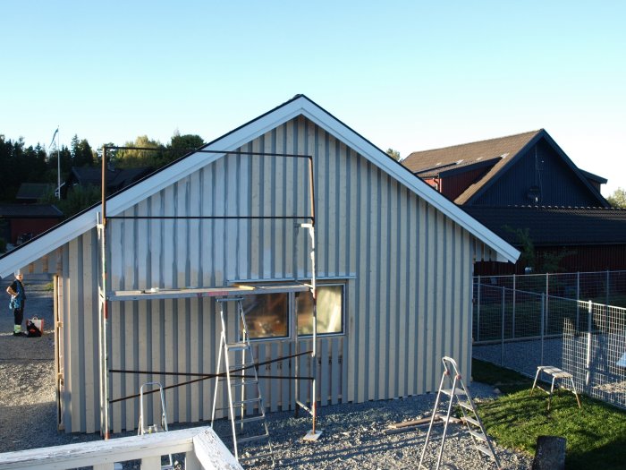 Hus under renovering med nästan färdigmonterad panel och synlig ställning.