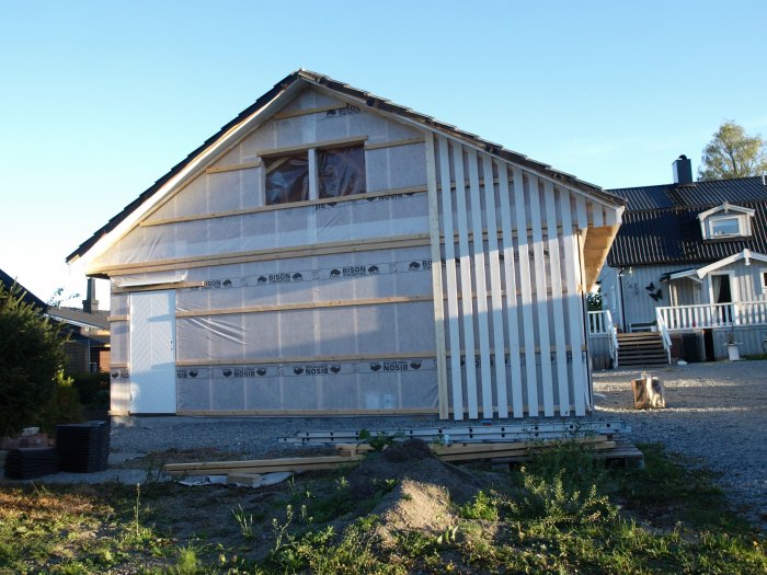 Hus under renovering med ny monterad väggpanel och förestående ombyggnad av porten.