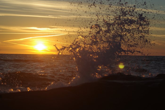 Solnedgång vid havet med en vattenskvätt framför i Halland.