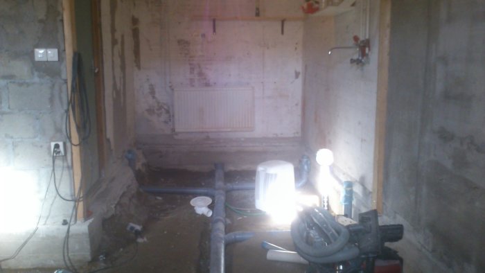Golv i källare med synliga rör och väggar i betong, förberett för gjutning.