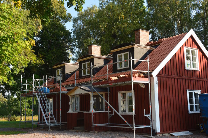 Renoverat rött hus med tegeltak och takstegar, vindskivor och målade takfotsbrädor.