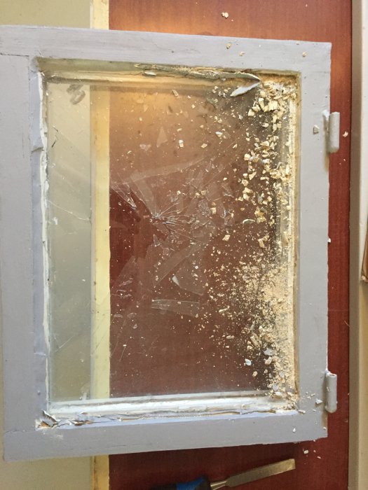 Sprucket källarfönster med trasigt glas ersatt med en ny plexiglasskiva och färskt kitt runt kanterna.