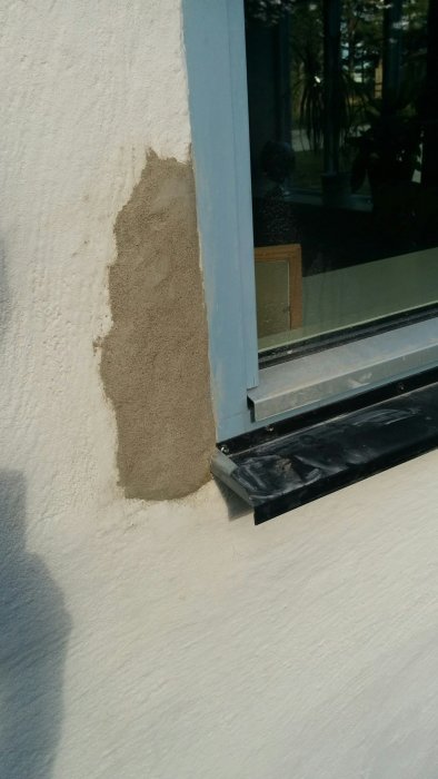 Nyapplicerad, härdande puts på en husfasad bredvid ett fönster.