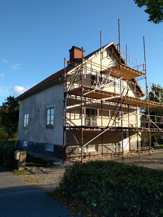 Byggnadsställning monterad längs en husfasad för reparation och putsarbeten.