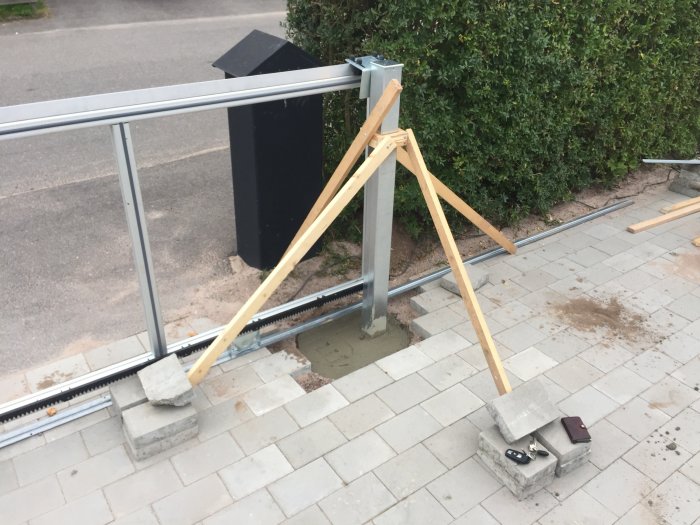 Installation av grindstolpar och förberedelse för skjutgrind vid en trädgård.