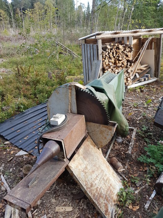 Gammal rostig vedkap med sågblad och 3-fas handske, utomhus nära vedbod, omgiven av skog.