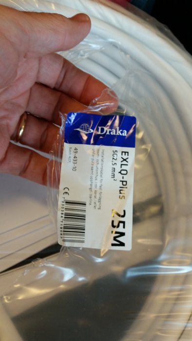 Hand håller Draka EXQ Plus kabel på rulle med etikett som visar 5g2.5 25m specifikationer.