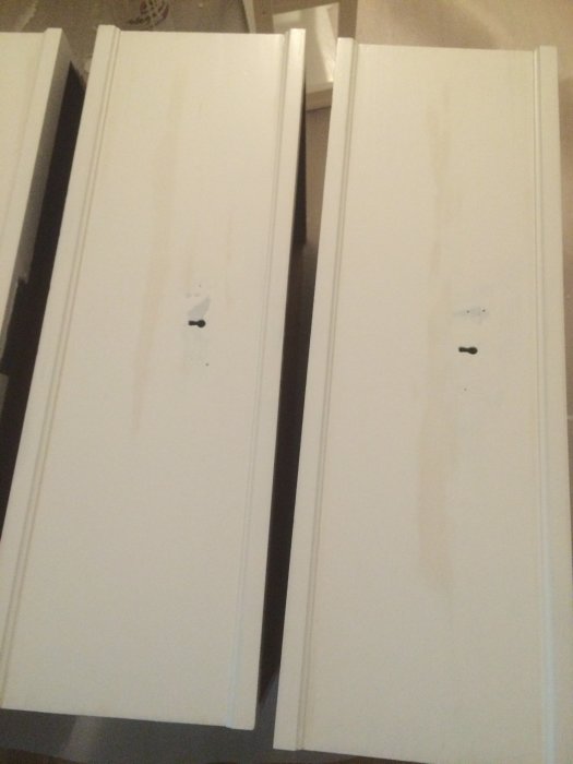 Byrå i trä målad vit där bruna ränder lyser igenom det vita lagret av lackfärg.