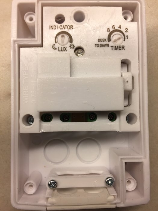 Baksida av en elektrisk timerenhet med inställningar för LUX och timer, oöppnad kabelanslutningsdel.