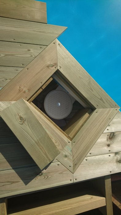 Trädäck med brädor runt ett hål där poolens skimmer syns, två trallbitar täcker delvis öppningen.