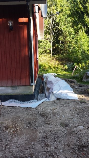 Östra sidan av ett hus under renovering, med grus och byggmaterial synliga vid husgrunden.