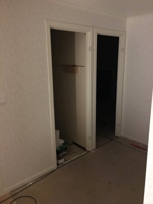 Panelad vägg och dörrkarmar med pågående installation av lister och takspottar.